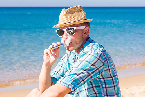 Vaping around the world hipster on a beach travel vape